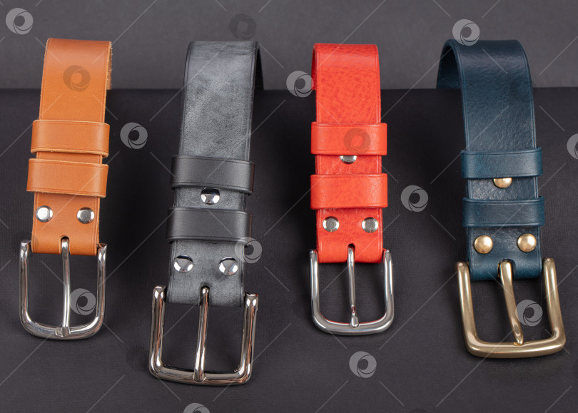 Скачать Разноцветный кожаный ремень с металлическими пряжками на темно-сером фоне. фотосток Ozero