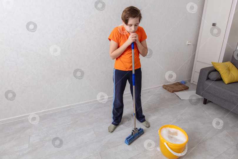Скачать Молодой человек убирает комнату, готовясь вымыть пол фотосток Ozero