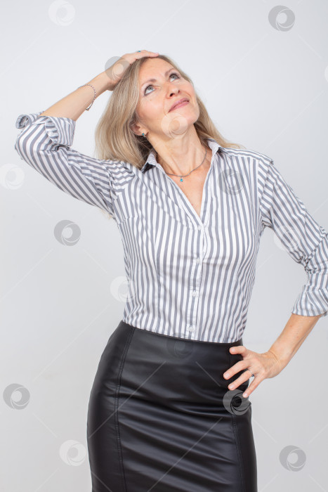 Скачать Уверенная в себе женщина позирует с задумчивым выражением лица, поправляя прическу в стильном наряде фотосток Ozero