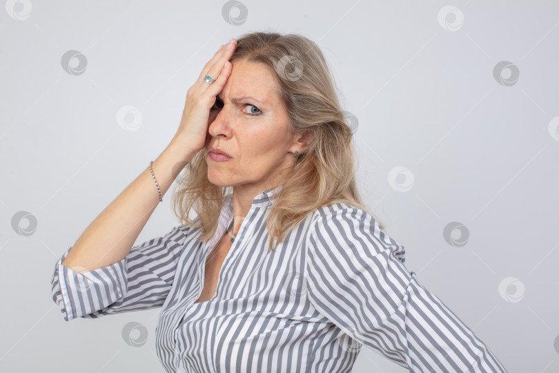 Скачать Расстроенная женщина в полосатой рубашке с озабоченным выражением лица на светлом фоне фотосток Ozero