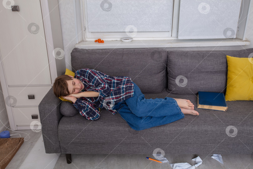 Скачать Ребенок отдыхает на диване в уютной домашней обстановке во второй половине дня фотосток Ozero
