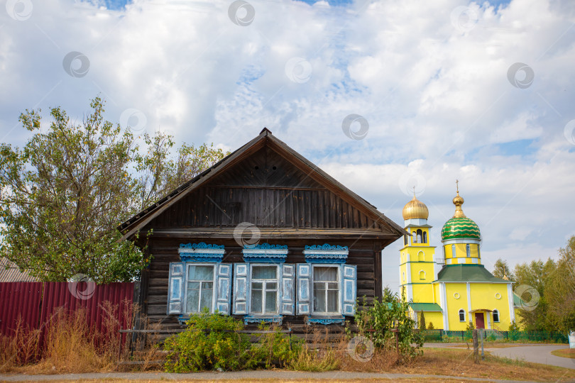 Скачать Традиционный деревянный дом рядом с красочной церковью в сельской местности в дневное время фотосток Ozero