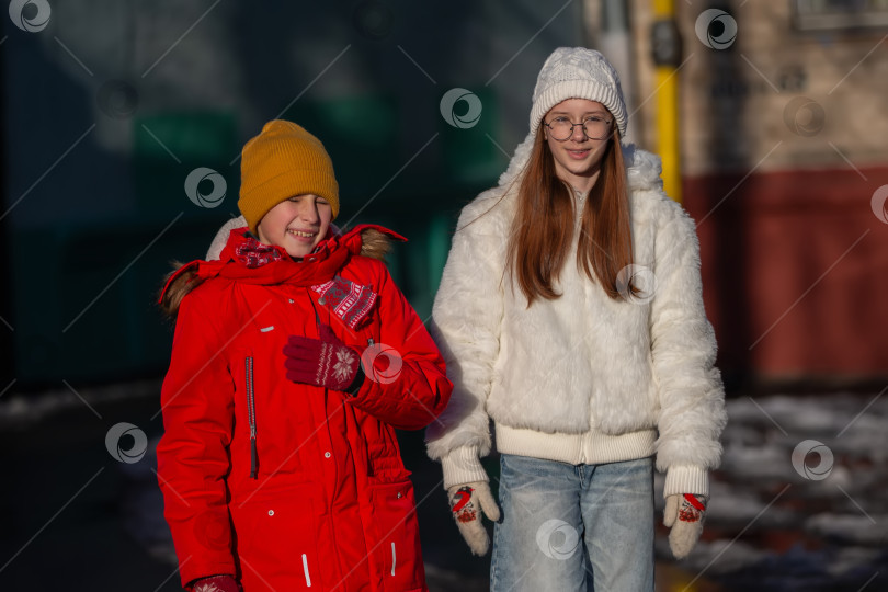Скачать Мальчик и девочка-подросток на фоне улицы. Они одеты в теплую зимнюю одежду. фотосток Ozero