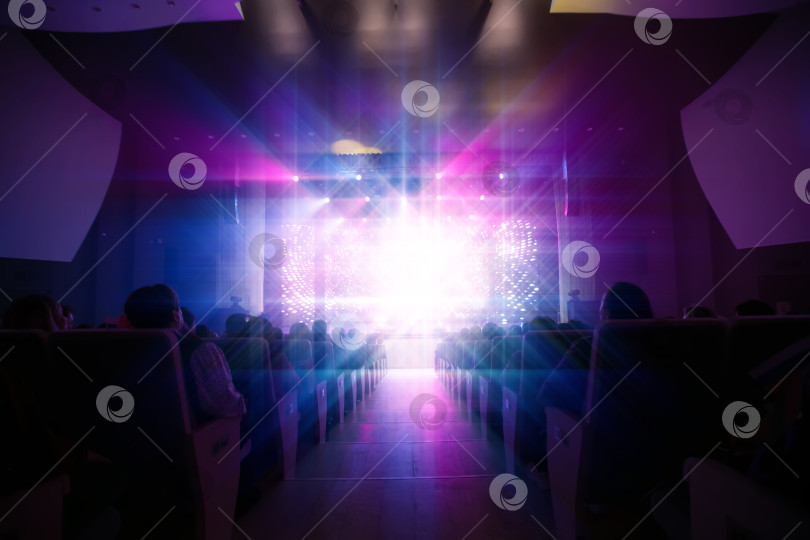 Скачать Яркие огни освещают публику, наслаждающуюся вечерним представлением в театре фотосток Ozero