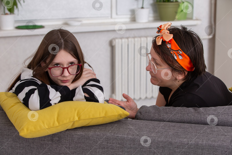 Скачать Мать и дочь ведут серьезный разговор на диване в уютной гостиной во второй половине дня фотосток Ozero