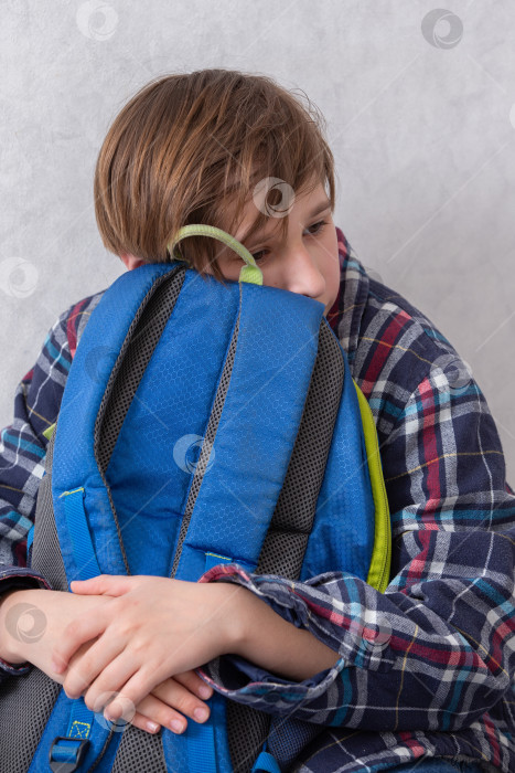 Скачать Ребенок отдыхает с синим рюкзаком, сидя в помещении в непринужденной и уютной обстановке тихим днем фотосток Ozero