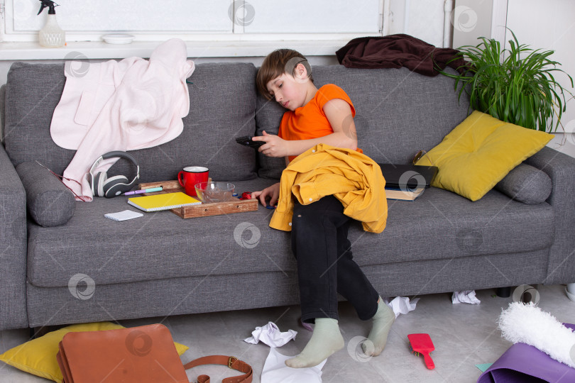 Скачать Ребенок отдыхает на диване в окружении домашнего беспорядка во второй половине дня фотосток Ozero