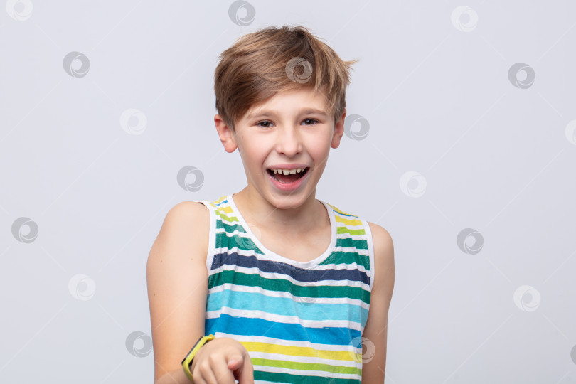 Скачать Мальчик смеется и игриво показывает пальцем, одетый в яркую полосатую майку в помещении фотосток Ozero