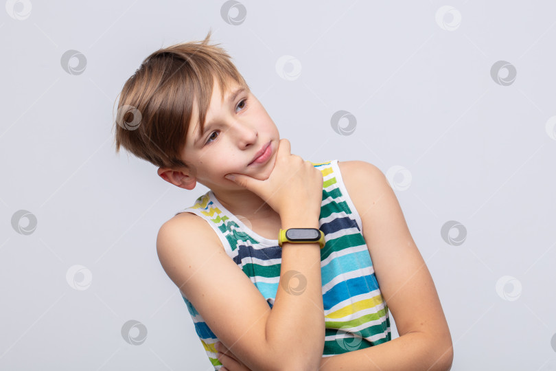 Скачать Мальчик в полосатой майке задумчиво размышляет на нейтральном фоне в дневное время фотосток Ozero