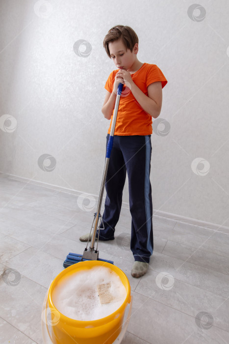 Скачать Маленький ребенок моет пол шваброй и ведром в уютном помещении фотосток Ozero