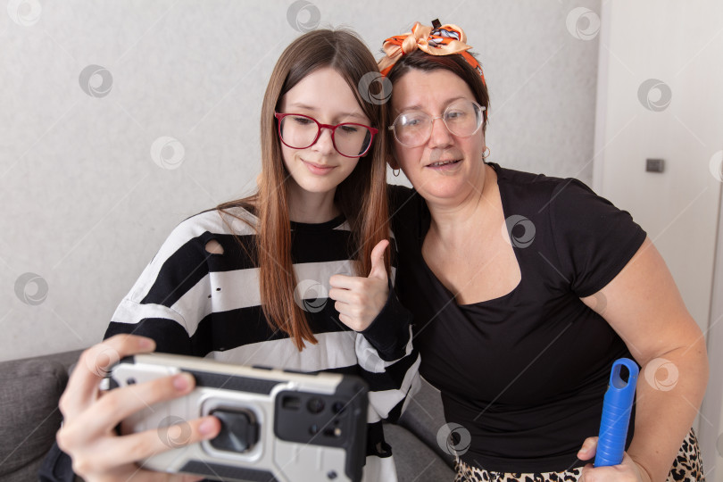 Скачать Две женщины делают совместное селфи в уютной гостиной, наслаждаясь приятным времяпрепровождением и смехом фотосток Ozero