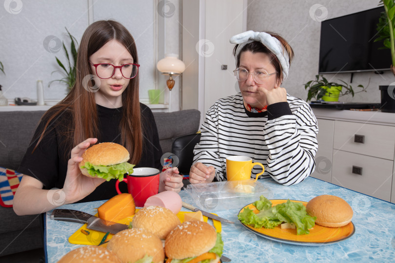 Скачать Семья наслаждается непринужденной трапезой вместе, готовя бургеры дома во второй половине дня фотосток Ozero