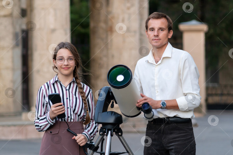 Скачать Молодая девушка и мужчина стоят у телескопа на открытом воздухе фотосток Ozero
