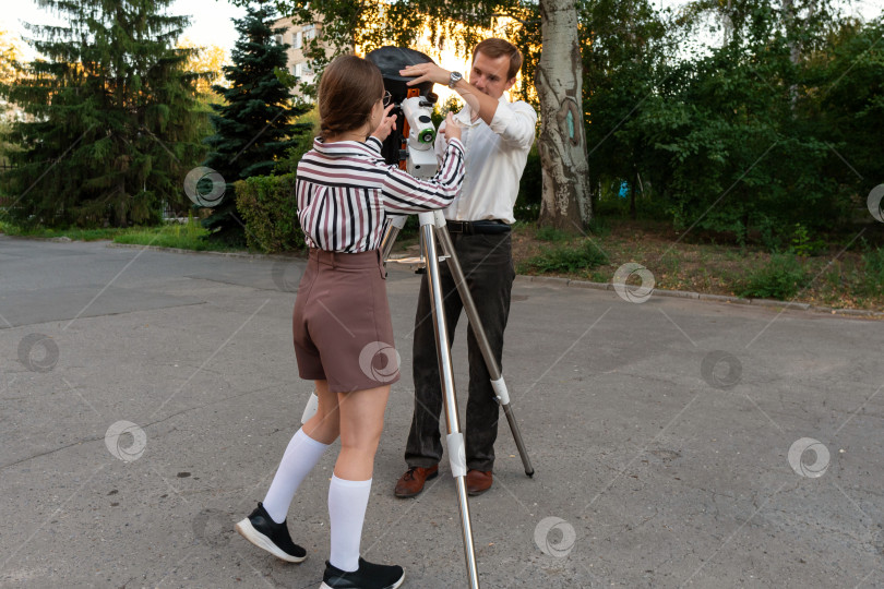 Скачать Учитель и девочка прикрепляют трубу телескопа к креплению фотосток Ozero