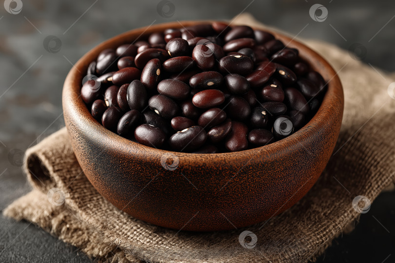 Скачать Миска в деревенском стиле, наполненная блестящими черными бобами, демонстрирующими свой глубокий цвет и красоту текстуры на фоне натуральной ткани фотосток Ozero