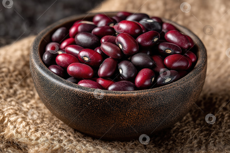 Скачать Крупный план Ярко-красной фасоли, уложенной в миску в деревенском стиле, демонстрирует ее сочные цвета и текстуру на уютном тканевом фоне фотосток Ozero