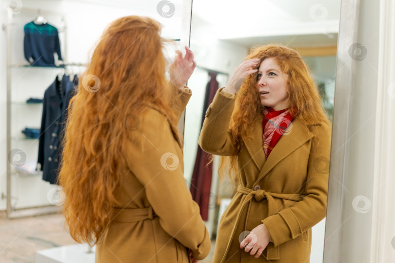 Скачать Женщина с рыжими волосами смотрит на себя в зеркало фотосток Ozero