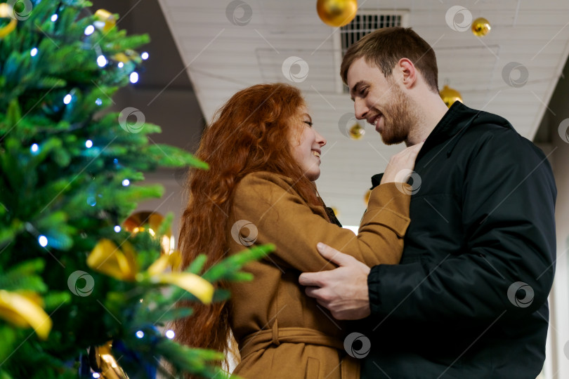 Скачать Мужчина и женщина обнимаются перед рождественской елкой фотосток Ozero