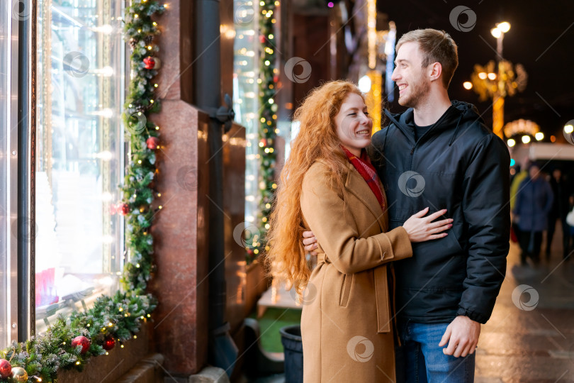 Скачать Мужчина и женщина обнимаются перед витриной с рождественскими украшениями фотосток Ozero
