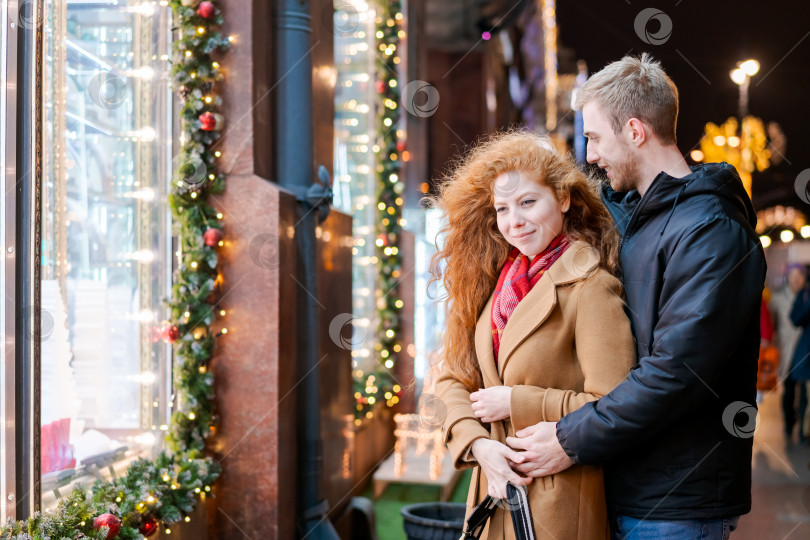 Скачать Мужчина и женщина стоят перед витриной с рождественскими украшениями фотосток Ozero