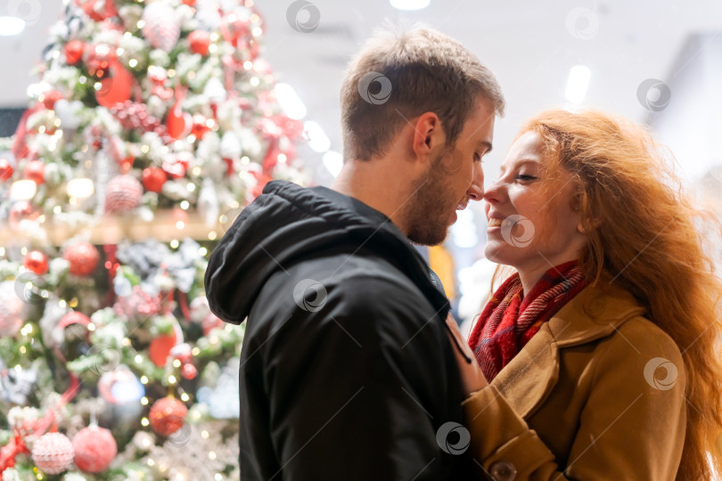 Скачать Мужчина и женщина обнимаются перед рождественской елкой фотосток Ozero
