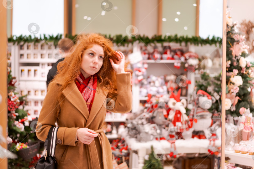 Скачать Рыжеволосая женщина смотрит на витрину с рождественскими украшениями фотосток Ozero