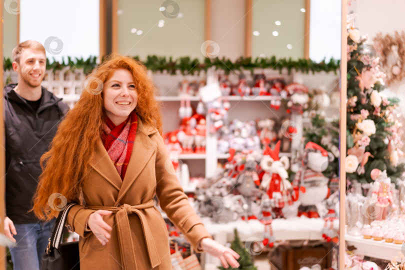 Скачать Рыжеволосая женщина заходит в магазин с мужчиной фотосток Ozero
