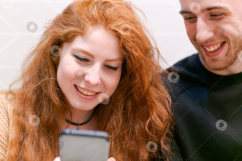 Скачать Рыжеволосая женщина смотрит в свой мобильный телефон фотосток Ozero