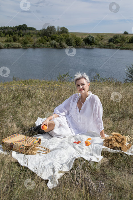 Скачать Пикник. Портрет женщины средних лет, сидящей на фоне озера фотосток Ozero