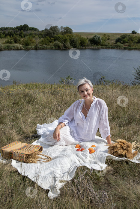 Скачать Пикник. Портрет женщины средних лет, сидящей на фоне озера фотосток Ozero