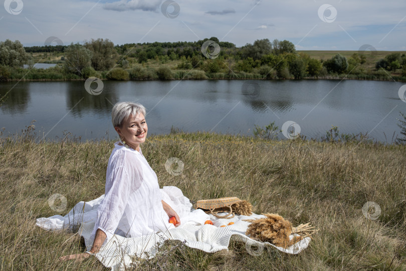 Скачать Пикник. Портрет женщины средних лет, сидящей на фоне озера фотосток Ozero