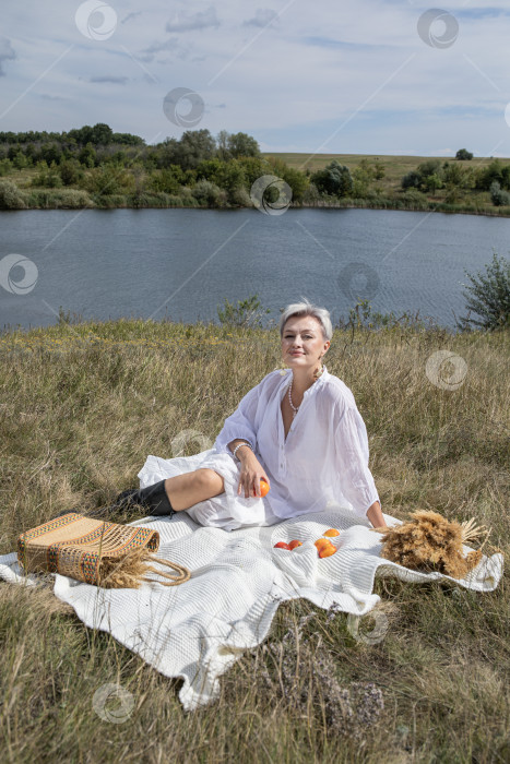 Скачать Пикник. Портрет женщины средних лет, сидящей на фоне озера фотосток Ozero