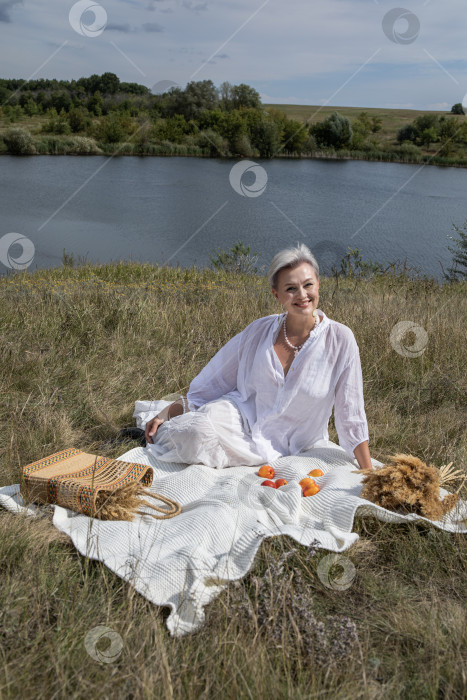 Скачать Пикник. Портрет женщины средних лет, сидящей на фоне озера фотосток Ozero