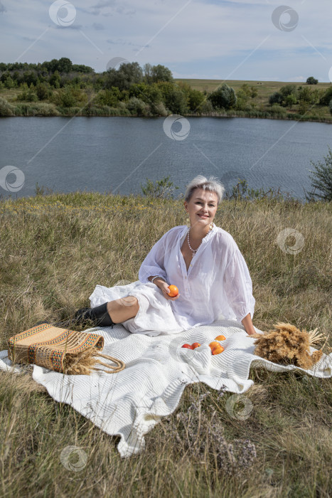 Скачать Пикник. Портрет женщины средних лет, сидящей на фоне озера фотосток Ozero