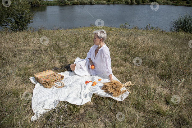 Скачать Пикник. Портрет женщины средних лет, сидящей на фоне озера фотосток Ozero