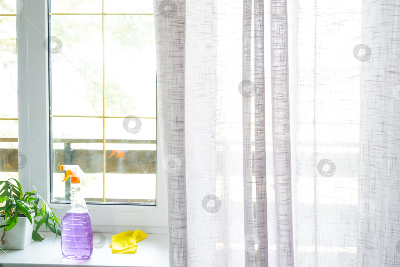 Скачать Средства для мытья окон лежат на подоконнике вместе с тряпкой, спреем, моющим средством. Генеральная уборка в доме, клининговые услуги фотосток Ozero