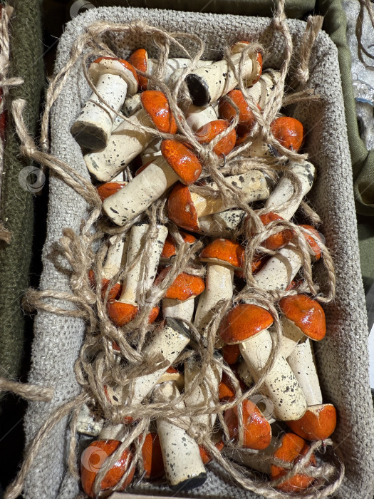 Скачать Декоративные украшения из оранжевых и белых грибов, перевязанные бечевкой, в плетеной корзинке фотосток Ozero