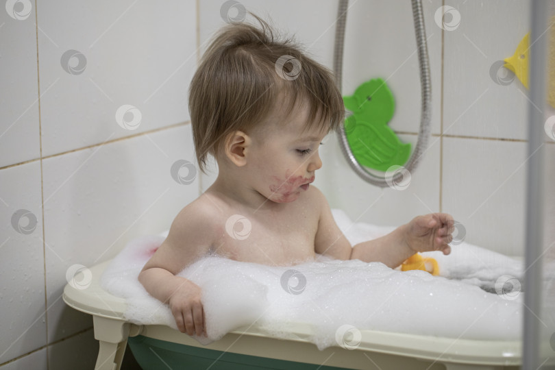Скачать Маленькая девочка купается, сидя в детской ванночке фотосток Ozero