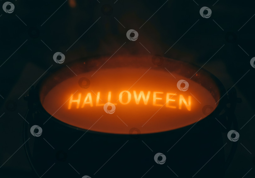 Скачать Светящаяся надпись на Хэллоуин внутри ведьминого котла, окутанного дымом. Жуткое сезонное украшение к празднику 31 октября. фотосток Ozero