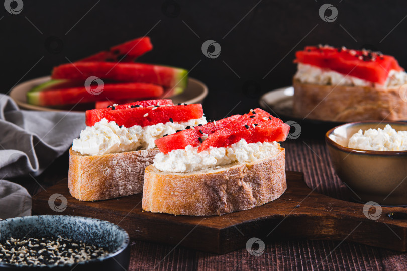 Скачать Вкусный бутерброд с рикоттой, арбузом и кунжутом на доске на столе фотосток Ozero