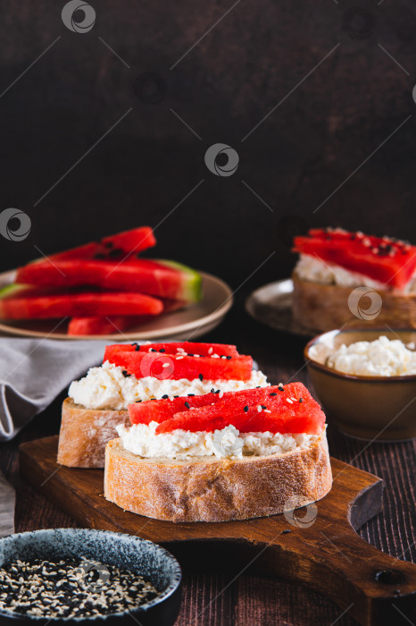 Скачать Вкусный сэндвич с рикоттой, арбузом и кунжутом на вертикальной доске фотосток Ozero