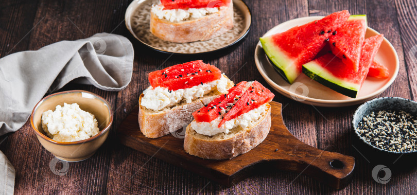 Скачать Вкусный сэндвич с рикоттой, арбузом и кунжутом на веб-баннере "доска на столе" фотосток Ozero
