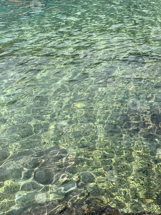 Скачать Прозрачная бирюзовая водная гладь создает абстрактные узоры с отражениями солнечного света и рябью фотосток Ozero