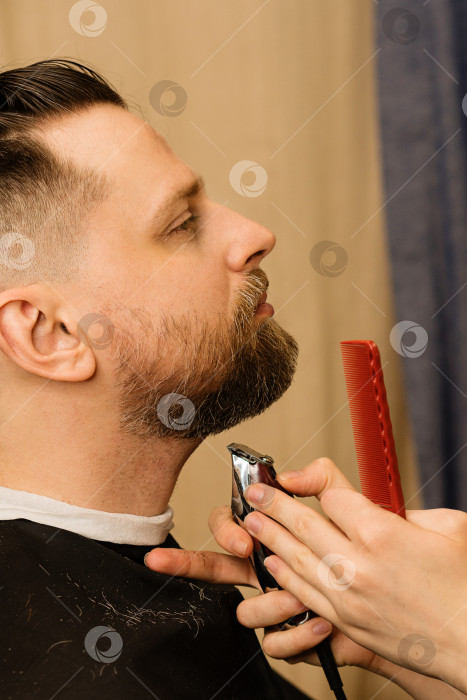 Скачать Парикмахер подстригает бороду электрической бритвой фотосток Ozero