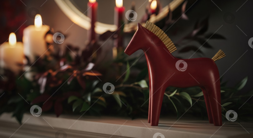 Скачать Статуэтка красной лошади на каминной полке с горящими свечами и зеленой листвой. Рождественское украшение фотосток Ozero