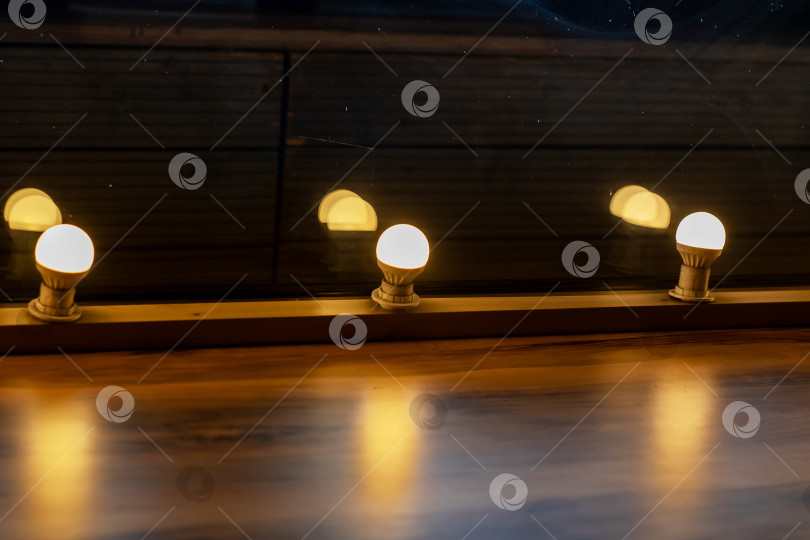 Скачать Длинный ряд ярких лампочек красиво подсвечивает деревянный пол фотосток Ozero