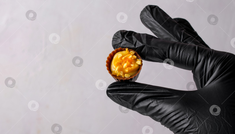 Скачать Шоколадный стаканчик для сладостей с манговой начинкой и апельсиновой крошкой в руках шеф-кондитера фотосток Ozero