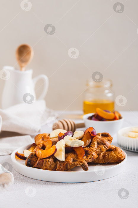 Скачать Сладкие крофли с бананом, сливой и медом на тарелке на столе, вид сверху фотосток Ozero