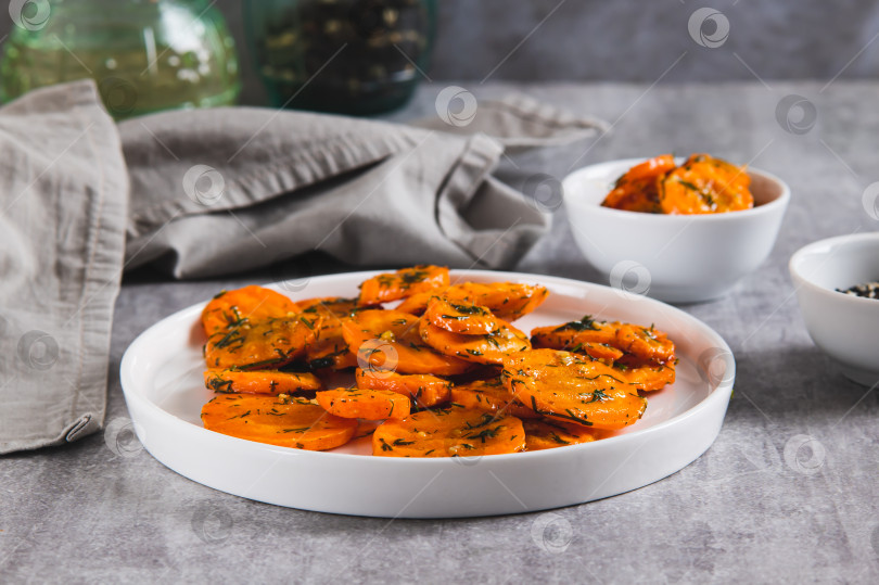 Скачать Кусочки обжаренной моркови с чесноком и зеленью на тарелке подаются на стол фотосток Ozero