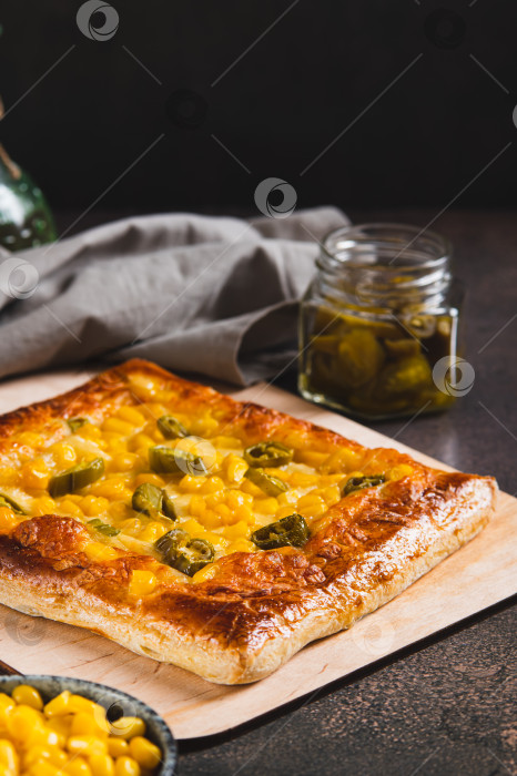 Скачать Острая пицца с перцем халапеньо, кукурузой и сыром на деревянной доске в вертикальном положении фотосток Ozero